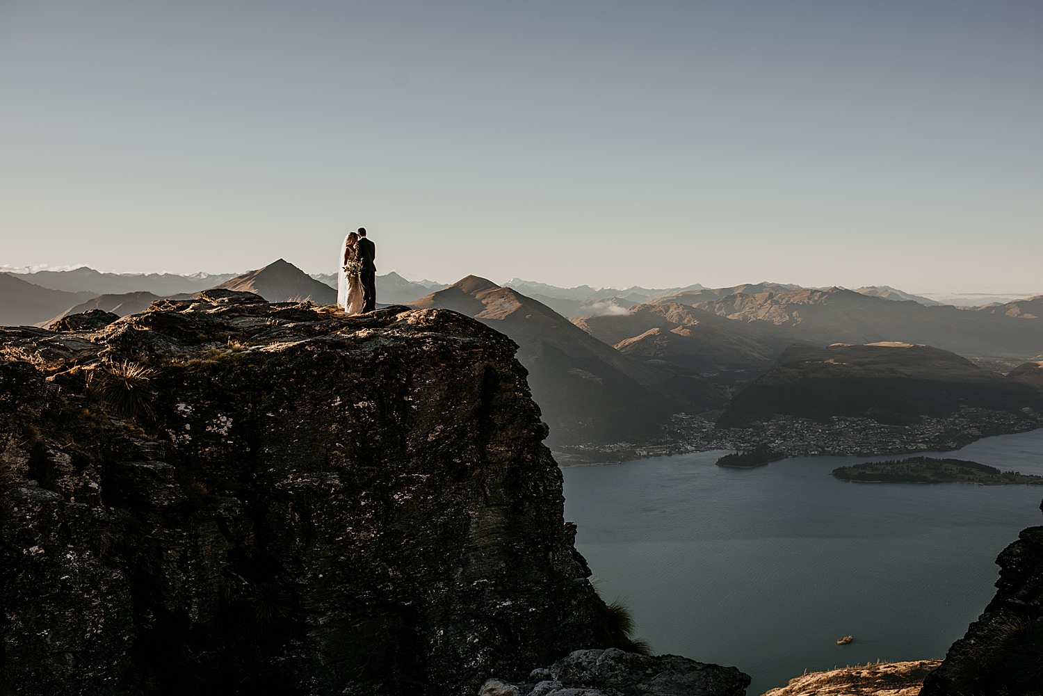 Wedding couple standing on the mountains, with a lake view inthe background, Queenstown Elopements