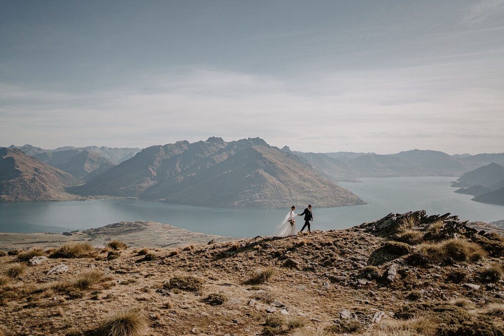 Newly wed couple standing on top of the Remarkable Mountain Range, after a Queenstown elopement.
