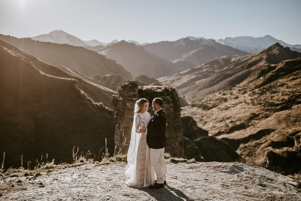 Wedding couple standing in the sunset with mountains in the background