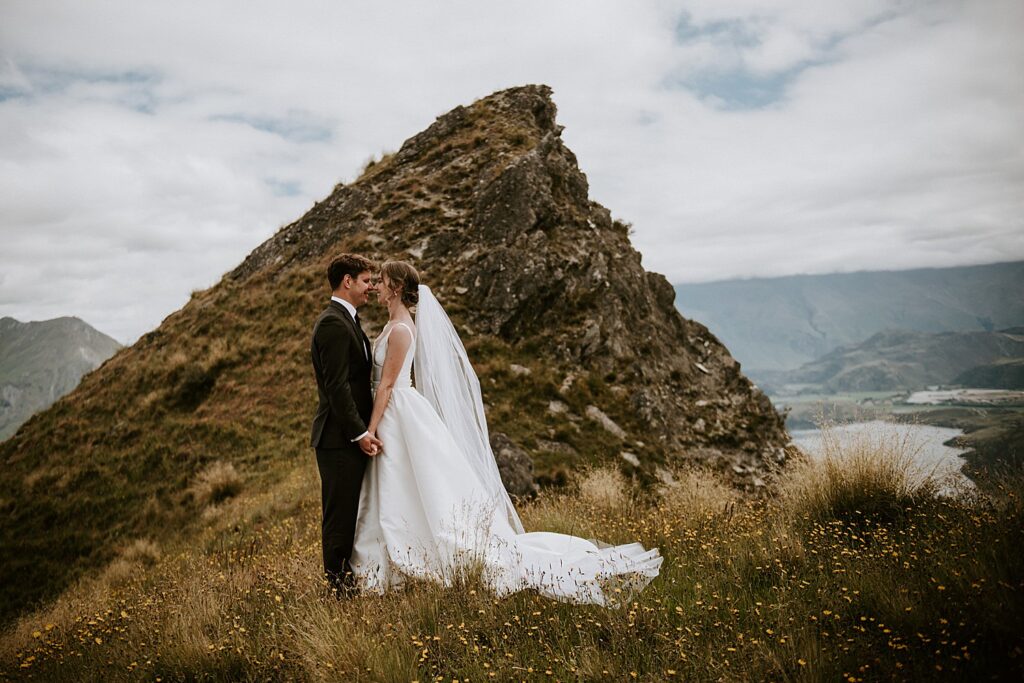 Mountain peak in the background of a wedding shot, bride and groom hand in hand looking into each others eyes