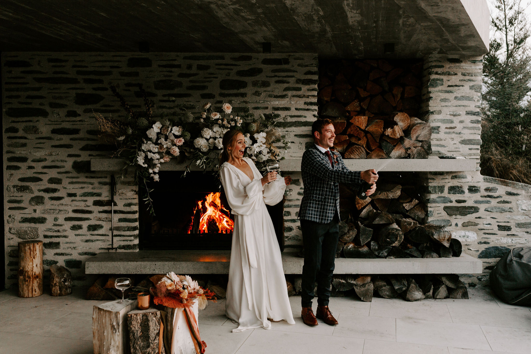 Elopement Packages Queenstown- Couple standing by and open fire popping bubbles on their wedding day