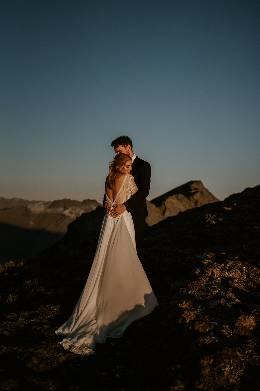 Elopement Packages Queenstown- Couple standing on top of Mt Crichton cuddling on their wedding day 